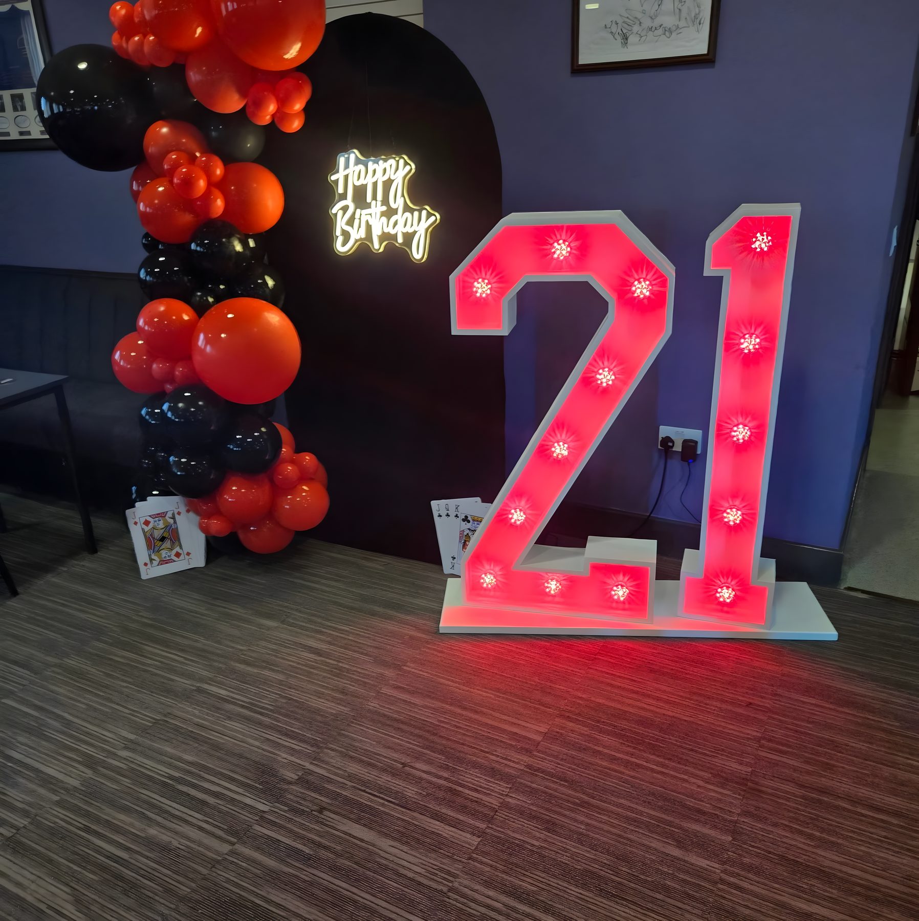 Red light-up 21 number with neon Happy Birthday sign and balloon garland